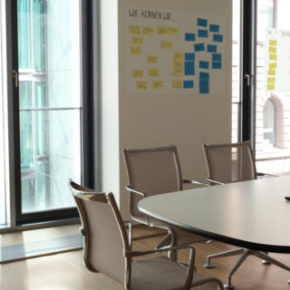 Großer heller Tagungsraum mit großem Tisch und Post Its an den Wänden